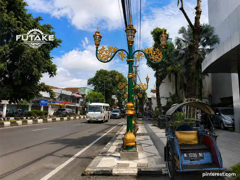 Ornamental pole dengan desain klasik yang digunakan sebagai tiang lampu dekoratif di ruang publik.